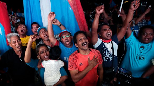 Opposition party supporters cheer and wave their party flags on election night.
