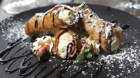 Cannoli shells filled with ricotta and drizzled with chocolate ganache.