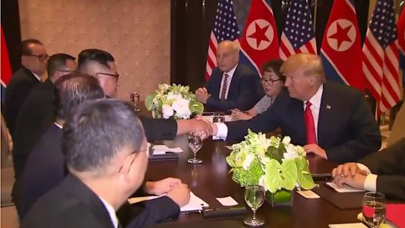 Trump and Kim shake hands with their advisers by their sides.
