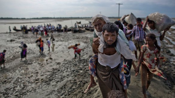 A Rohingya Muslim man from Myanmar carries an elderly woman after they crossed the border into Bangladesh from Myanmar, in Teknaf, Bangladesh.