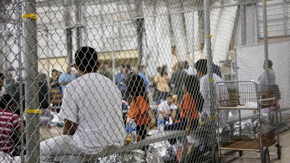 People taken into custody related to cases of illegal entry into the United States, sit in one of the cages at a facility in McAllen, Texas.