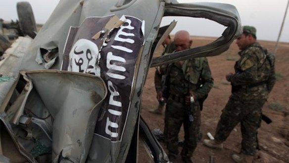 Destruction: Peshmerga fighters inspect the remains of a car that belonged to Islamic State militants in Baqufa, north of Mosul.