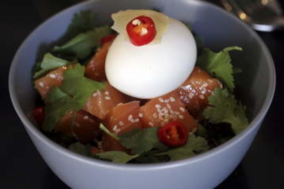 Salmon sashimi on wild rice with a soft egg and pickled ginger.