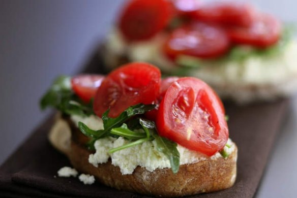Ricotta cheese on toast with sliced tomatoes and rocket