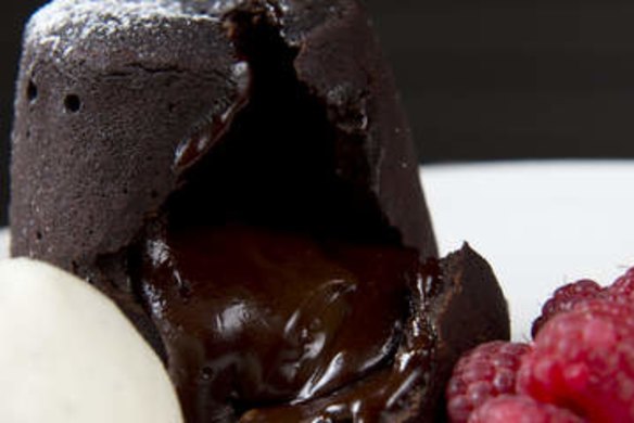 An opened hot chocolate fondant with vanilla ice cream.