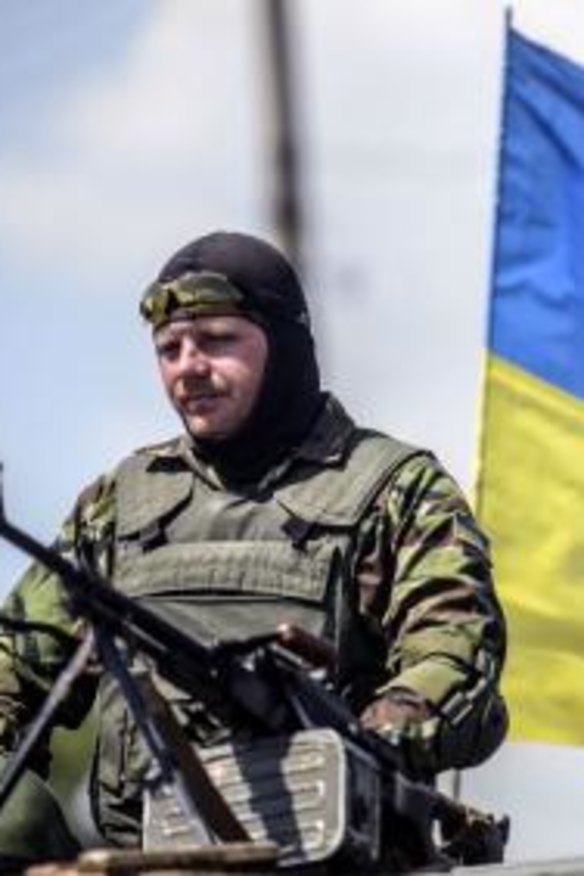 A Ukrainian soldier near Donetsk on top a humvee with a Ukrainian flag behind him on Thursday.