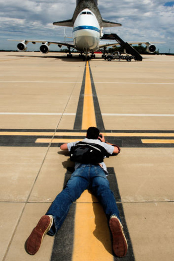 A photographer gets down low for a shot of the Space Shuttle Discovery after it's final landing on the back of a NASA's Boeing 747 Shuttle Carrier Aircraft( at Washington, Dulles International airport.