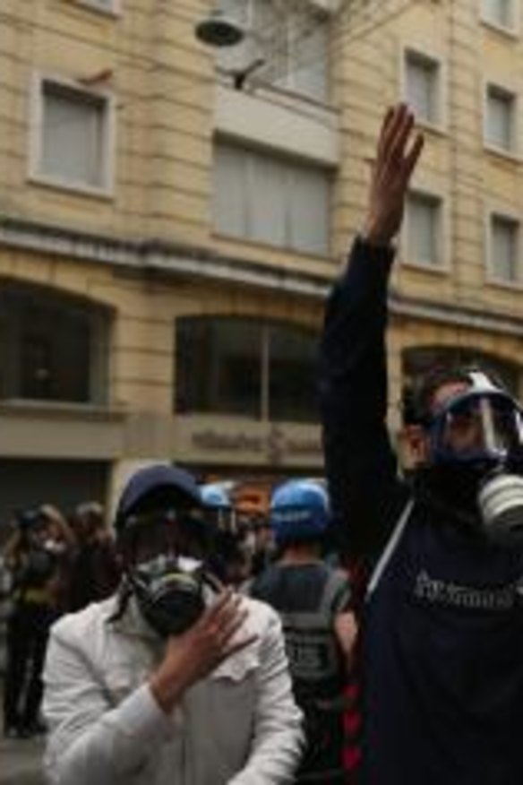 A masked policeman raises his arms in Istanbul's fashionable Istiklal Avenue during the anniversary protests.