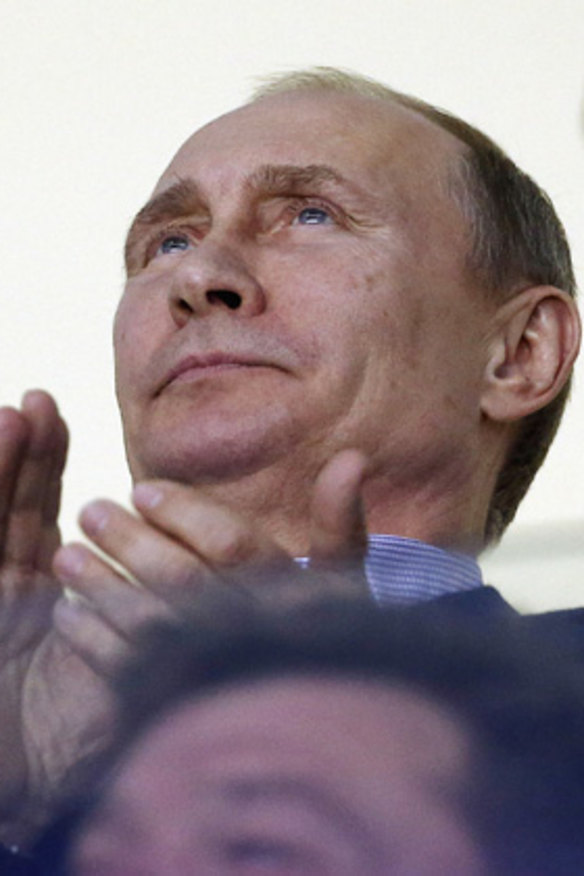Russian President Vladimir Putin claps during the third period of a men's ice hockey game between the USA and Russia at the 2014 Winter Olympics.