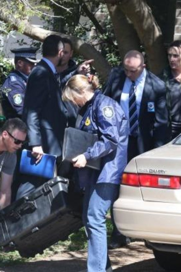 Police leave with what appears to be a sword after a raid in Sydney on Thursday.