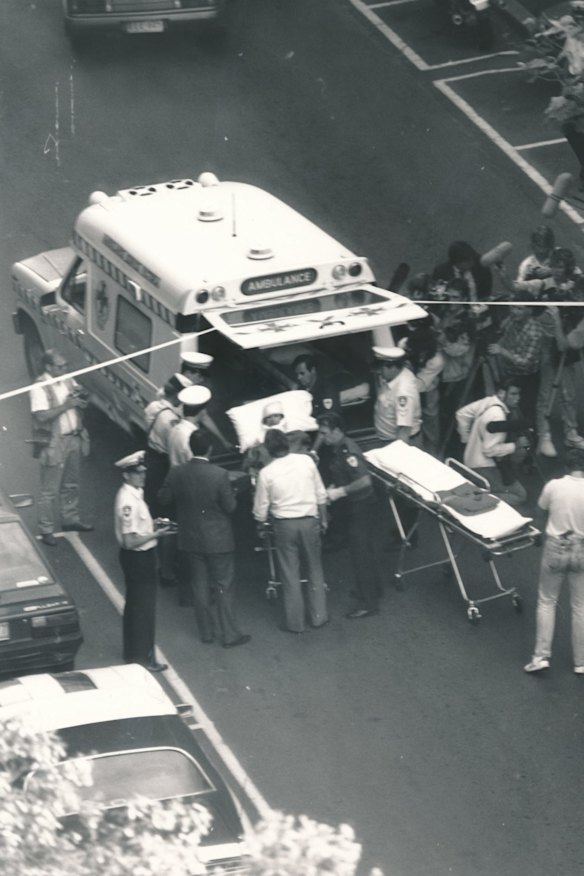 Ambulance workers and police surround a victim of the Queen Street Shooting before they're loaded into an ambulance.