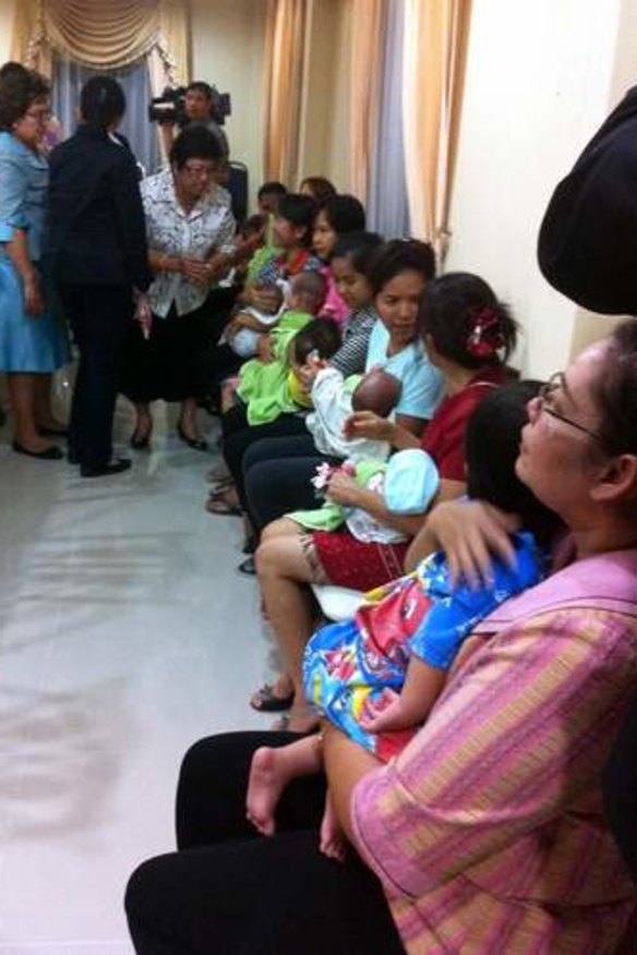 Nannies hold some of the nine babies alleged to be the surrogate children of one Japanese man after a police raid at a Bangkok apartment.