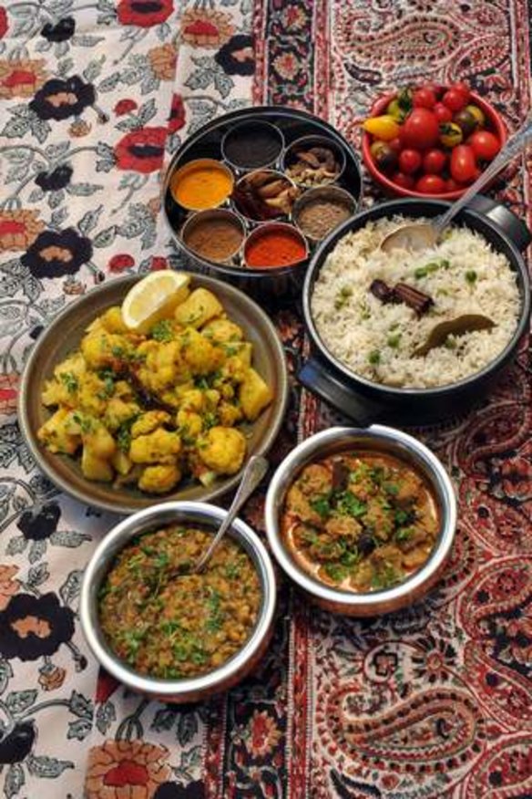 Clockwise, from bottom centre, Punjabi dhal (maa chole ki dal), Aloo gobi (cauliflower and potatoes with spices), an assortment of spices, tomatoes, Jeera rice (Cumin rice) and Rogan josh (Kashmiri lamb curry).