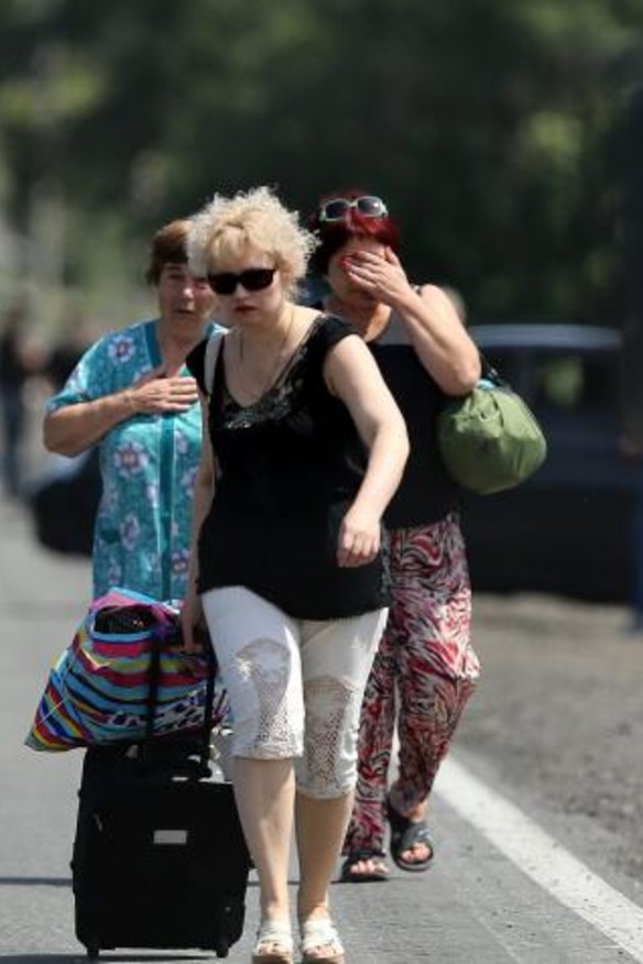 Fleeing residents of Shakhtersk carry their belongings in bags as they run to waiting cars on the outskirts of the city during heavy shelling.