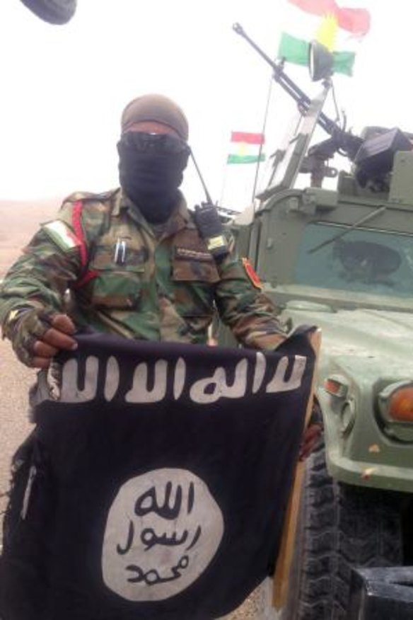 Message: A Kurdish fighter pulls down a flag belonging to Islamic State militants at the Mosul Dam on Tuesday.