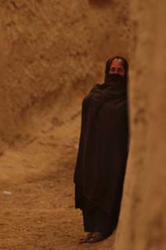 Out of the shadows: A woman stands in the laneways in Sakhar village, Uruzgan Province, Afghanistan.