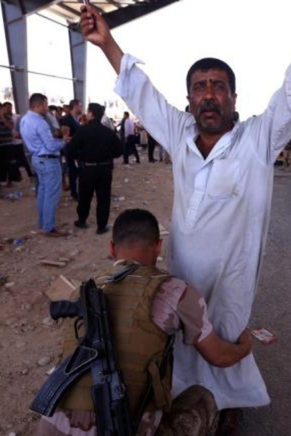 A security guard from Kurdish forces frisks a man fleeing the violence in Mosul.