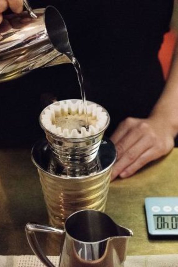 A barista prepares pour-over coffee at Gumption by Coffee Alchemy.