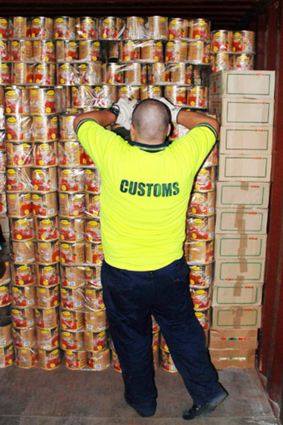Cans of worms: An Australian Customs officer with some of the tomato cans containing ecstasy tablets in Melbourne in 2008.
