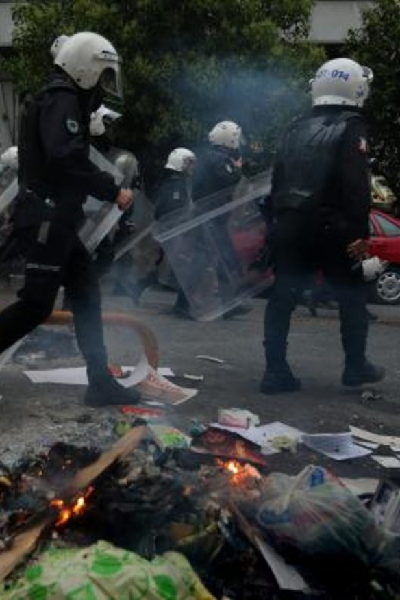 Police walk past burning debris in Istanbul's Cihangir district during the anniversary protests.