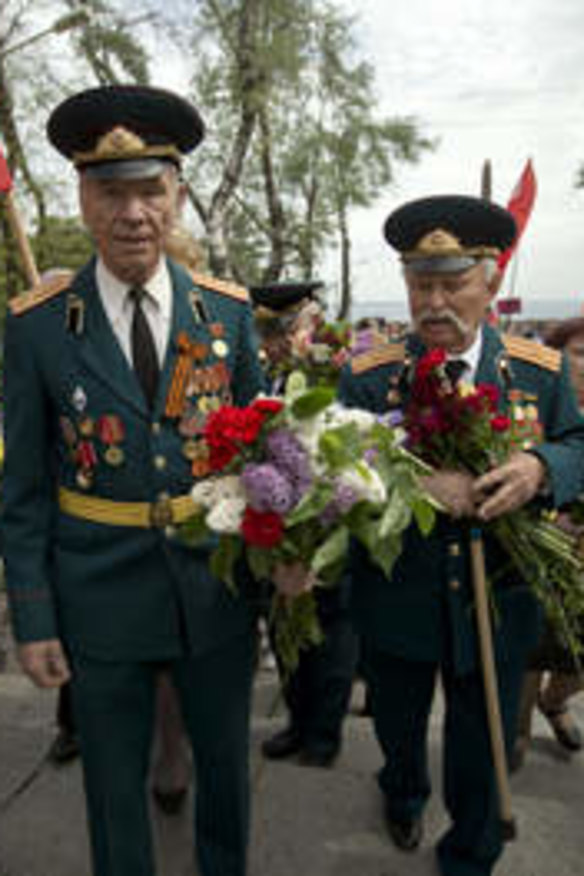 World War II veterans carry flowers given to them by people attending Victory Day celebrations on Friday.