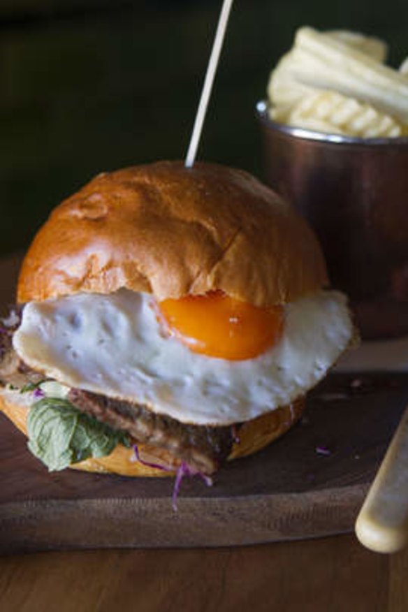 Brisket and fried egg sandwich with a side of salt and vinegar chips.