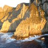 Wet and wild ... the cruise boat passes the soaring cliffs of Tasman Island.