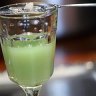 Sugar dissolves atop an absinthe spoon into a glass of absinthe.