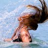 Woman tosses back her wet hair while bathing in Muri Lagoon.