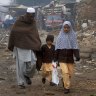 Cold comfort: A man walks his children home from school in the north-western city of Peshawar after the massacre. 