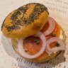 A bagel topped with salmon, red onion and cream cheese.